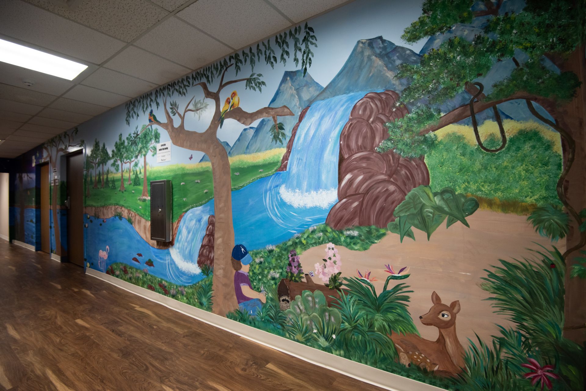 Handpainted mural of a waterfall and forest in Bourbon Community Hospital's Adolescent Behavioral Health Unit.